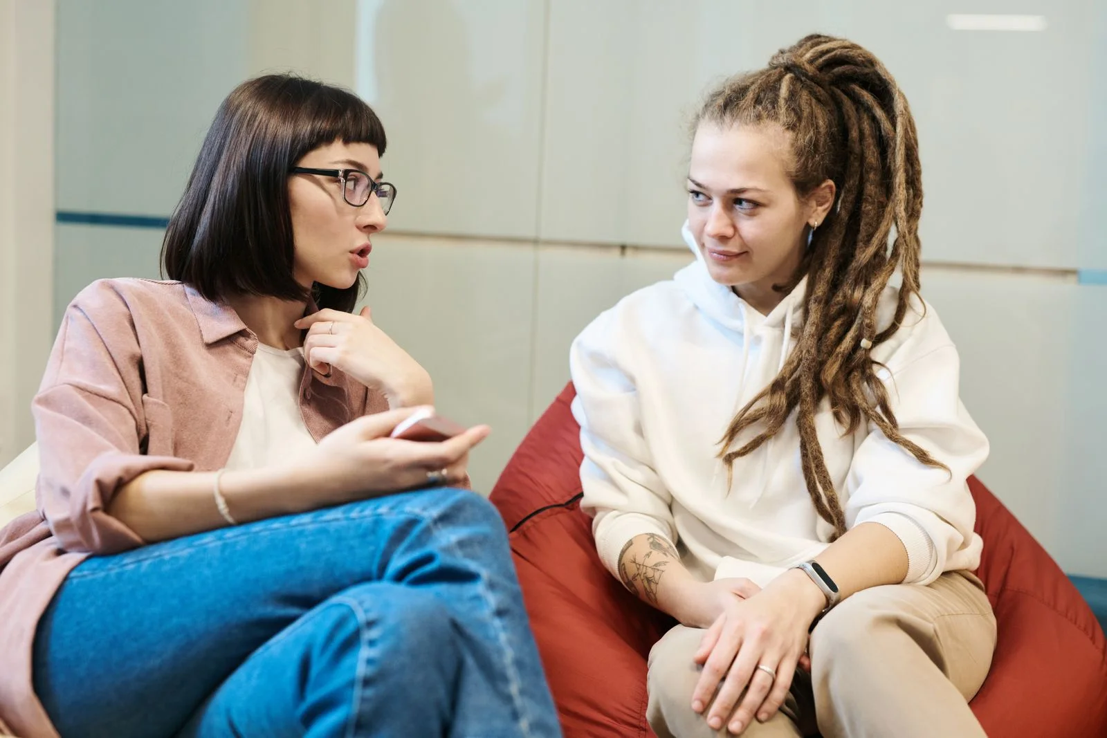 Deux jeunes femmes en pleine conversation, installées sur des poufs