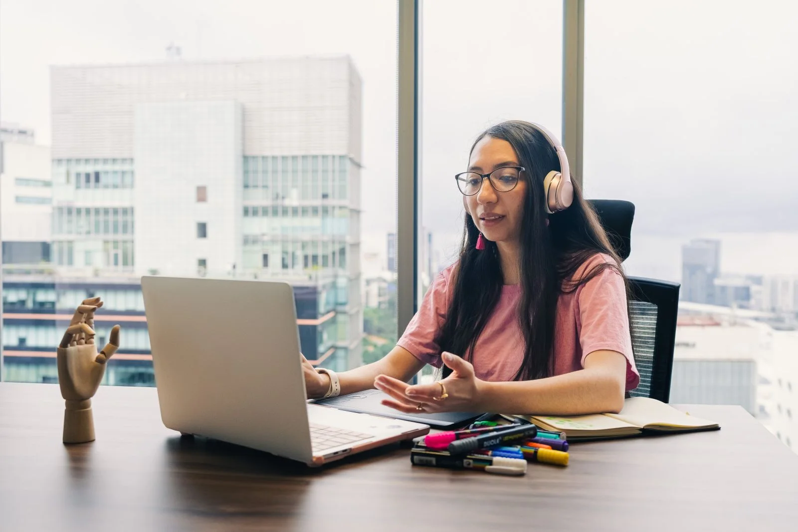 Une jeune femme au casque en visioconférence devant une grande baie vitrée
